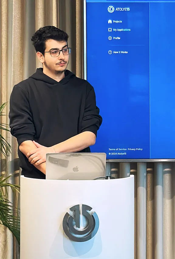 Three developers gathered around a laptop, engaged in a focused discussion.